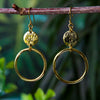 A pair of Kenyan brass earrings hanging on a rustic stick. Siesta UK
