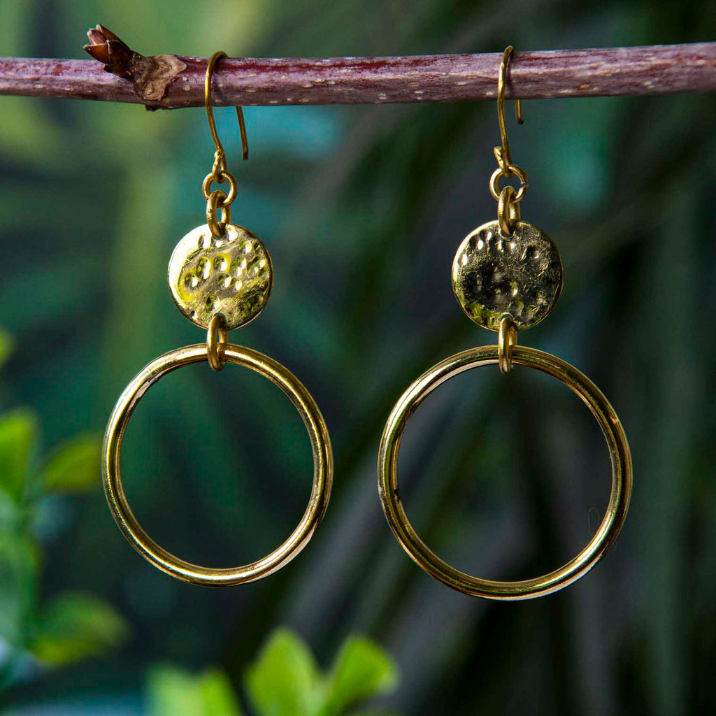 A pair of Kenyan brass earrings hanging on a rustic stick. Siesta UK