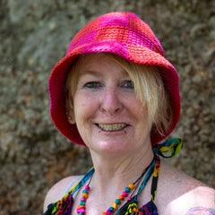 Woman wearing a colorful crocheted hat against a textured wall.