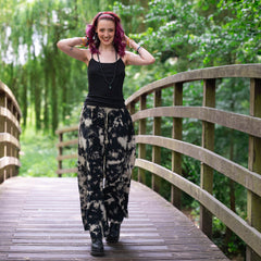 Woman with purple hair standing on a wooden bridge in a forest