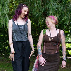 Two women standing outdoors with greenery in the background