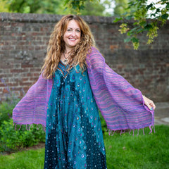 Woman wearing a teal dress with a purple shawl in an outdoor setting