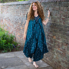 Woman in a teal dress standing against a brick wall