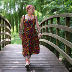 Woman in a colorful dress walking on a wooden bridge in a forest